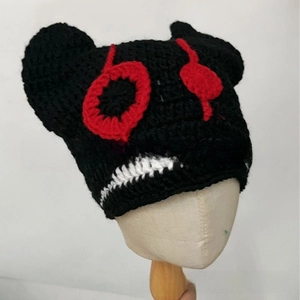 Detailed macro view of handmade black knitted hat featuring devil horns and crochet textures