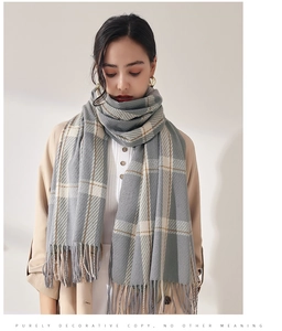 Détail d'une écharpe à carreaux gris et beige avec franges et texture élégante