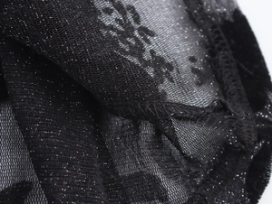 Detailed close-up of black mesh fabric with silver glitter finish and seam details