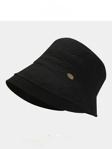 Detailed view of black bucket hat with 3D crinkle texture and metal oval emblem