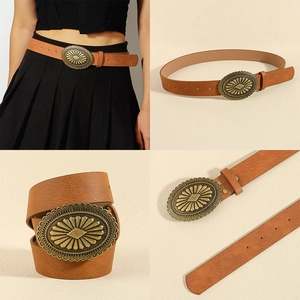 Detail view of brown vintage leather belt with ornate gold alloy buckle and floral engraving