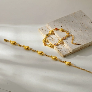 Détail macro de bracelets dorés avec breloques cœur et goutte en zircons colorés