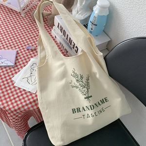 Detailed texture of off-white canvas tote bag with green botanical print on a chair