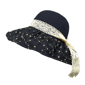 Close-up of wide-brim black straw hat with white floral embroidery and lace ribbon