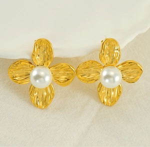 Macro shot of gold-plated petal earrings with hammered texture and white pearls