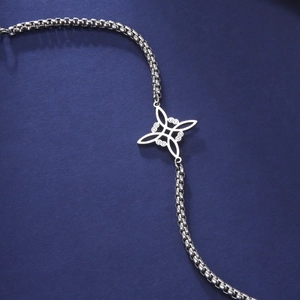 Macro shot of silver stainless steel box chain bracelet featuring a Celtic knot pendant
