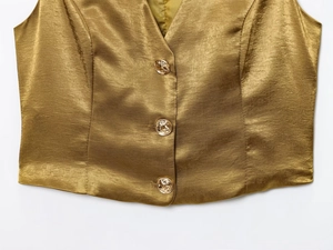 Detailed close-up of golden satin waistcoat featuring three metallic textured buttons