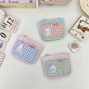 Detailed view of three quilted coin purses with bear patches and heart stitching