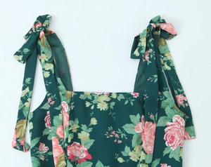 Detail of dark green floral midi dress with pink roses and shoulder bow ties