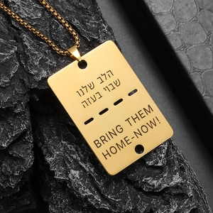 Macro detail of gold dog tag pendant with Hebrew engraving on black textured stone