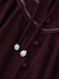 Detail of burgundy textured shirt featuring white stitching and beaded tassel ties