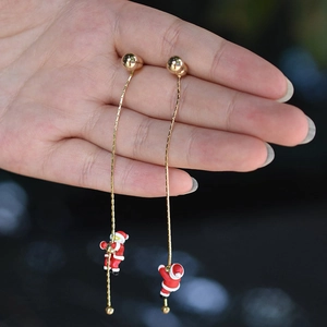 Gros plan détaillé des boucles d'oreilles de Noël avec Père Noël grimpant et chaîne or