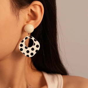 Detail of vintage polka dot resin earrings worn by a model in warm natural light