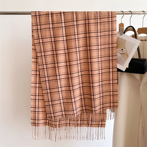 Détail d'une écharpe à carreaux camel montrant la texture douce et les franges à la mode