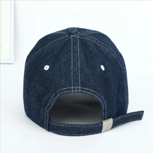 Detail of adjustable metal buckle and contrast stitching on denim baseball cap