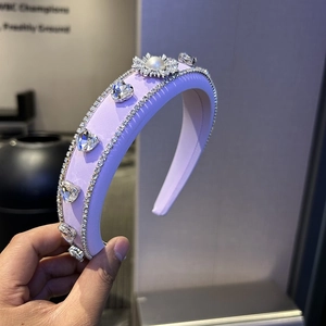 Close-up of lavender satin headband with crystal hearts and a pearl floral accent