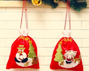Close-up of red velvet Christmas gift bags with embroidered Santa and Snowman hanging on wall