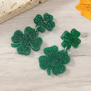 Detail shot of green glitter clover earrings on a rustic wood background
