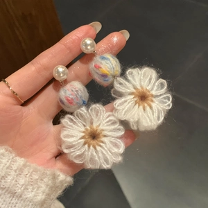 Detailed view of handmade knit daisy flower earrings with elegant pearl stud accents