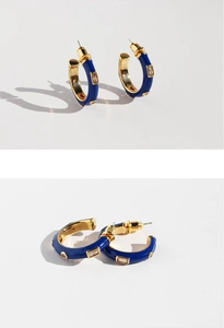 Macro detail of hand-painted blue enamel C-shape hoop earrings with rectangular zircon