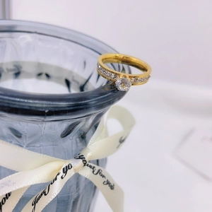Elegant gold titanium ring with starburst setting displayed on a blue decorative vase