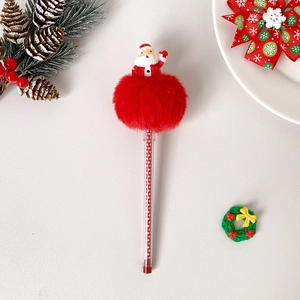 Detail view of a Christmas ballpoint pen with red pom pom and Santa topper on a festive desk