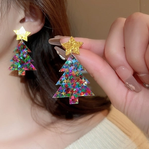 Sparkly gold star and glittery acrylic Christmas tree earrings worn by a model
