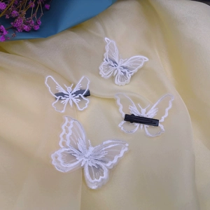 Detailed view of four white lace butterfly hair clips on elegant yellow silk fabric