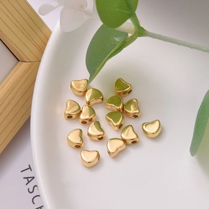 Polished golden heart spacer beads for DIY jewelry making displayed on a clean plate
