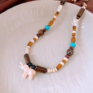 Dettaglio di collana di perle colorate con ciondolo a forma di elefante rosa nel piatto