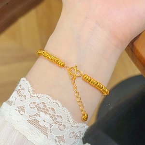 Macro shot of gold-plated oval bead bracelet featuring an S-hook clasp and heart pendant