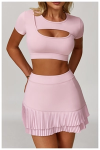 Detail of pink two-piece yoga set with cutout short sleeve top and pleated tennis skirt