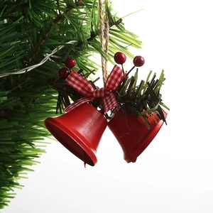 Detail of red Christmas bells with holly berries and bow hanging on pine branch
