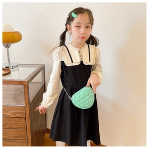 Detail of a mint green heart-shaped quilted chain bag worn by a young girl model