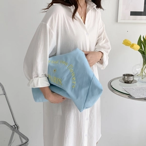 Detail of light blue canvas tote bag with yellow floral embroidery and Paris typography