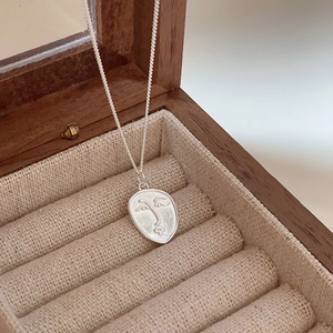 Close-up of 925 sterling silver abstract face pendant on a wooden jewelry display