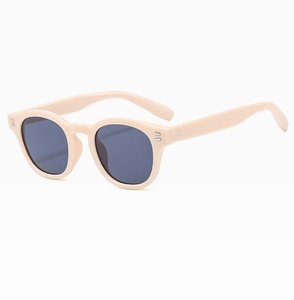 Detail of retro cream round sunglasses with dark lenses and stylish metallic rivets