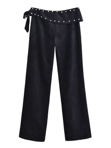 Detail of black high-waisted flare trousers with silver rivets and side bow accents