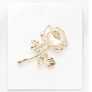 Detail of rose brooch with golden metal finish and inlaid mother of pearl petals