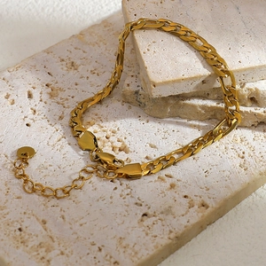 Λεπτομέρεια από επιχρυσωμένο βραχιόλι Figaro 18K με κούμπωμα καβούρι σε πέτρινη βάση