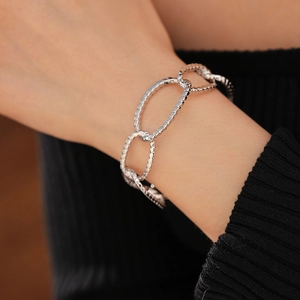 Detailed view of silver oval link bracelet with textured finish worn on a model wrist