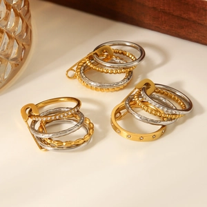 Macro shot of gold and silver layered rings with crystal inlay and safety pin link detail