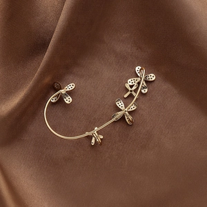 Close-up of gold-plated bow ear clips with small zircons on brown satin background