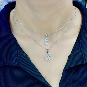 Detail shot of silver Arabic letter pendants with inlaid crystals on elegant necklaces