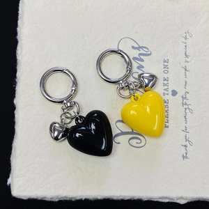 Detail of colorful resin heart keychains in black and yellow with silver metal clips