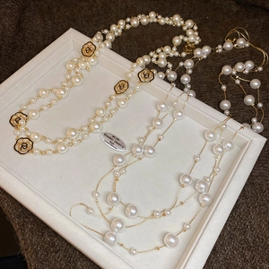 Detailed close-up of vintage pearl necklaces with black enamel camellia flower pendants