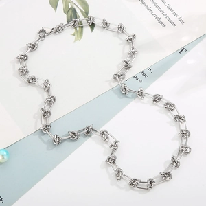 Close-up of a silver-toned knot link chain necklace on a clean minimalist white background