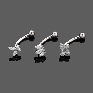 Detailed macro view of G23 titanium curved barbells with zircon butterfly and flower designs