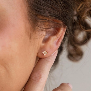 Macro view of gold flower earrings with white pearls in a four-leaf clover design