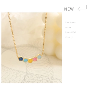 Dettaglio di una collana dorata con cinque ciondoli a forma di smile in smalto colorato